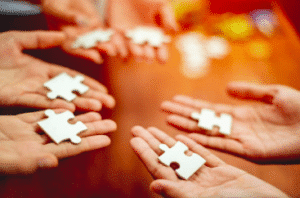 Jeu coopératif : des mains font un puzzle ensemble.